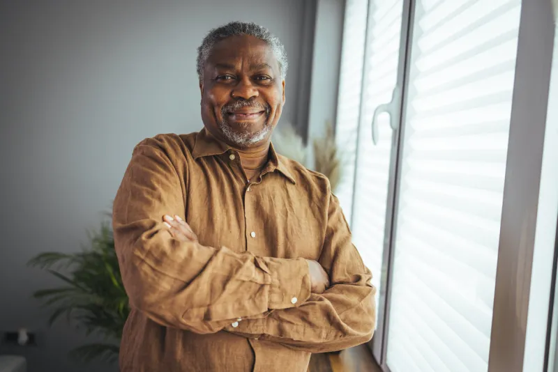 african american senior man at home portrait smiling senior man looking at camera portrait of black confident man at home portrait of a senior man standing against a grey background