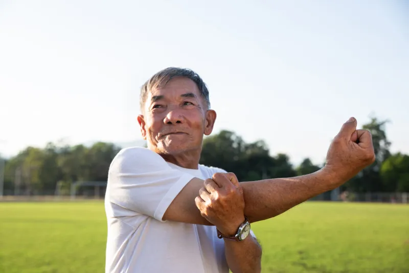 senior man is exercising in the park doing stretch, healthy retirement lifestyle health care and old people concept