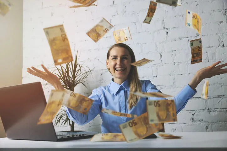 successful cheerful business woman throwing euro banknotes in office falling money
