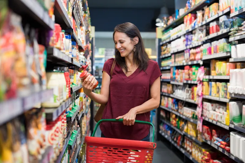 happy mature woman looking at product at grocery store smiling hispanic woman shopping in supermarket and reading product information costumer buying food at the market