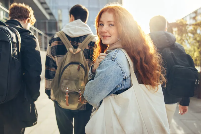 female student glancing back while going for a class in college girl walking with friends going for class in high school