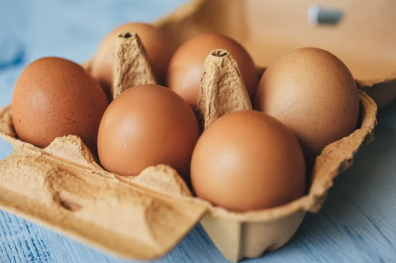 eggs background closeup view of eggs in carton box on wooden table food and health concept