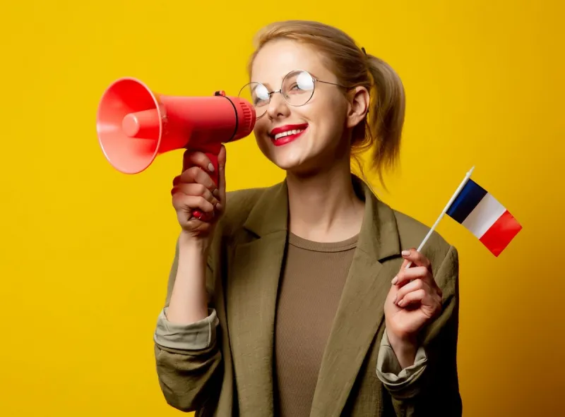 style blonde woman in jacket with french flag and megaphone on yellow background