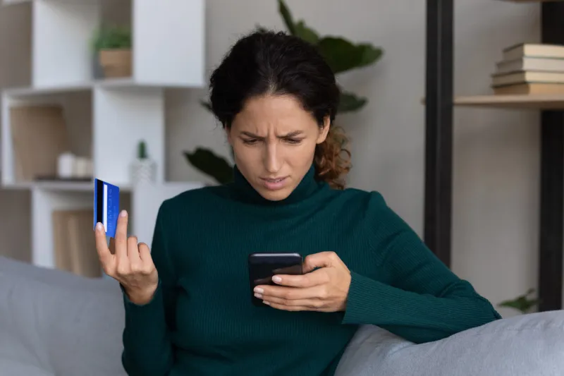 internet scam concerned young hispanic lady looking on smartphone screen having finance savings stolen from bank card as money fraud result upset nervous latin woman become online scammers victim