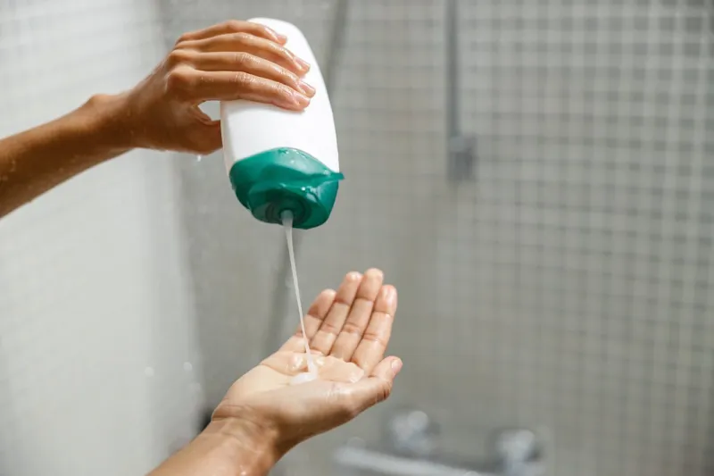 woman pouring shower gel on her hand when taking shower hygiene concept high quality photo