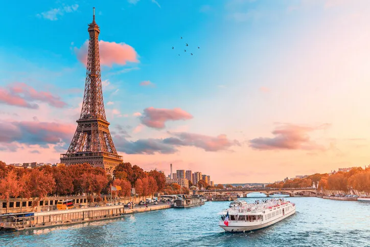 the main attraction of paris and all of europe is the eiffel tower in the rays of the setting sun on the bank of seine river with cruise tourist ships
