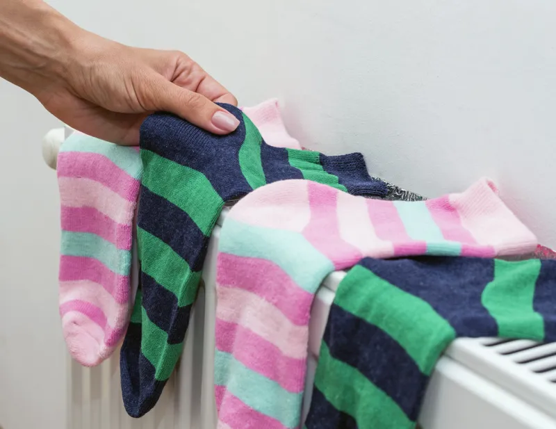 woman's hand hold socks that dry on radiator domestic heating radiator