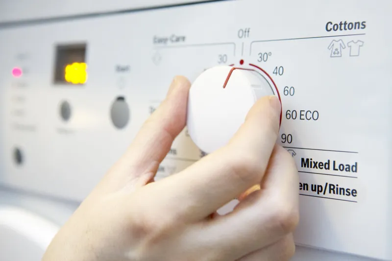 woman selecting cooler temperature on washing machine to save energy