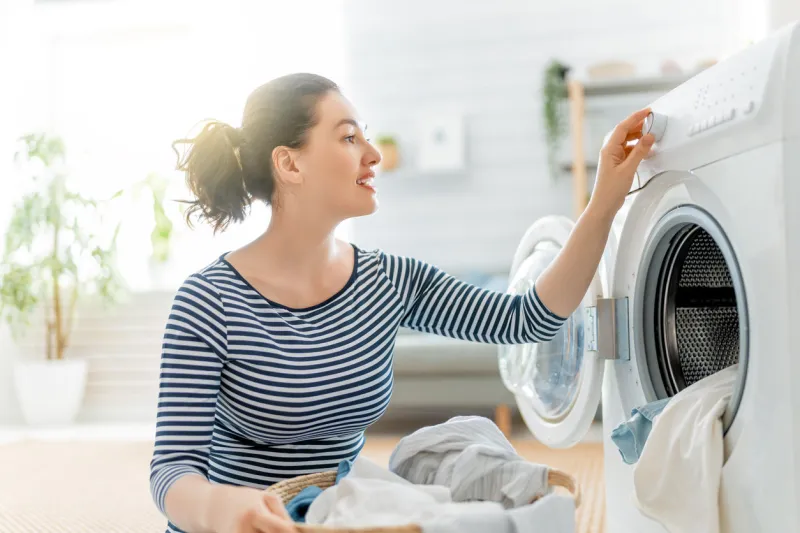 beautiful young woman is smiling while doing laundry at home