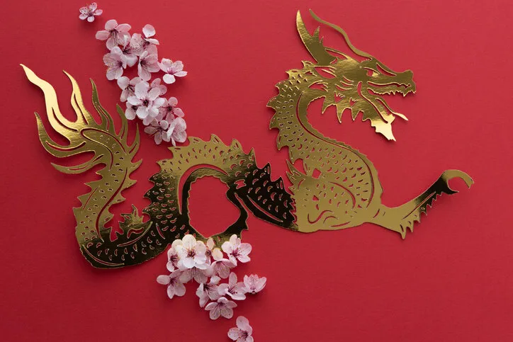 chinese new year dragon cut out in gilt paper with plum blossom decoration on red background copy space top view