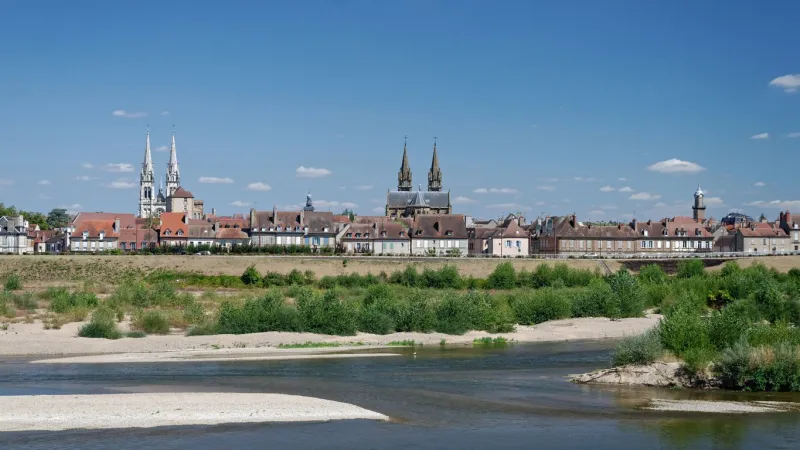 a panoramic view of the french city of moulins by the allier river a cathedral, a church as well as old houses are visible