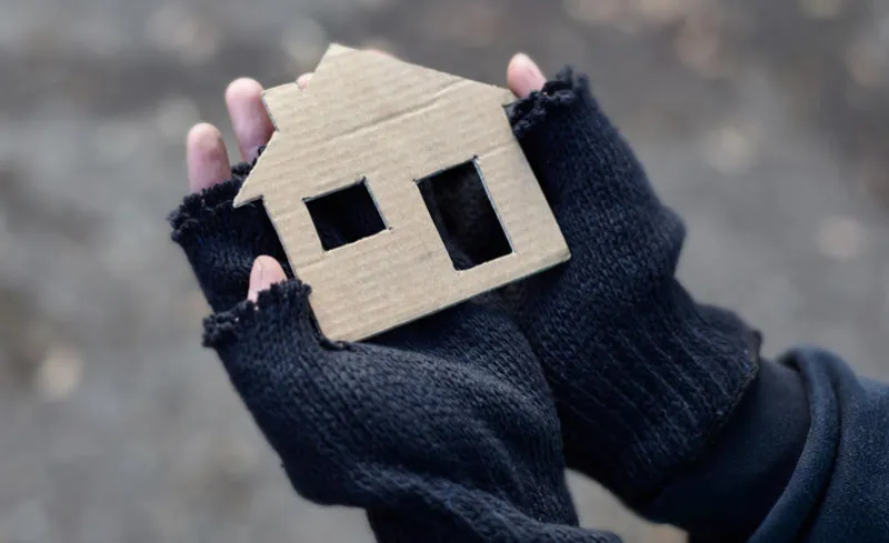 young homeless boy holding a cardboard house