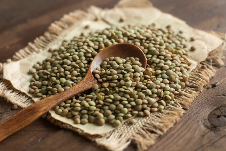 green lentils with a spoon on a wooden table top view