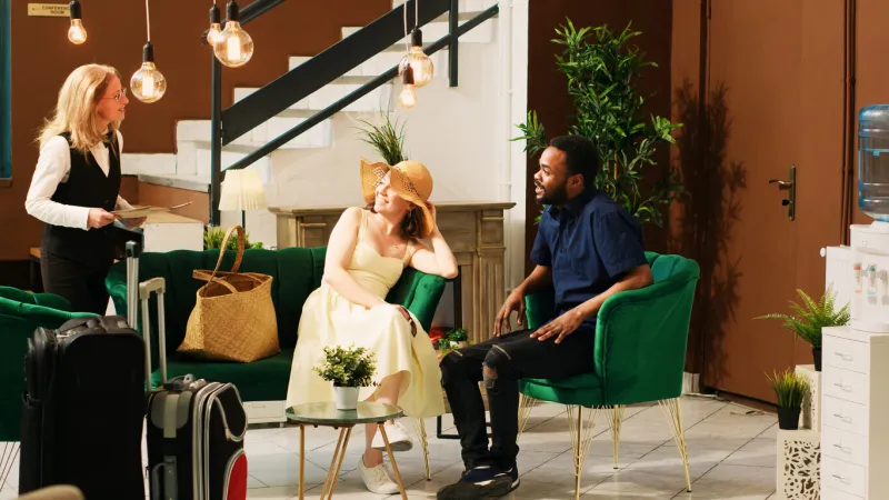 hotel staff talking to guests in lobby, offering luxury services to people waiting in lounge area employee recommending tropical leisure activities to couple with room reservation