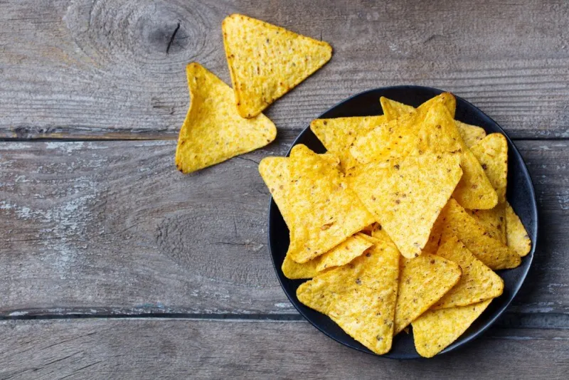 nachos, corn chips on black plate wooden background top view copy space