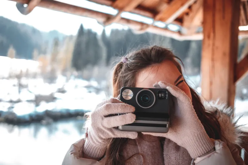young woman photographing with retro instant film camera for vintage style picture