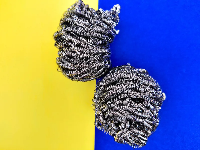 two stainless steel sponge for dish washing isolated on yellow and blue background