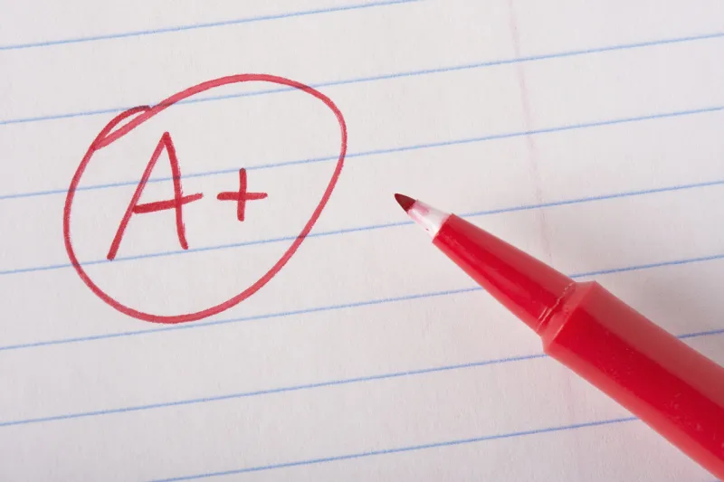 a plus (a+) grade written in red pen on notebook paper with the pen sitting there