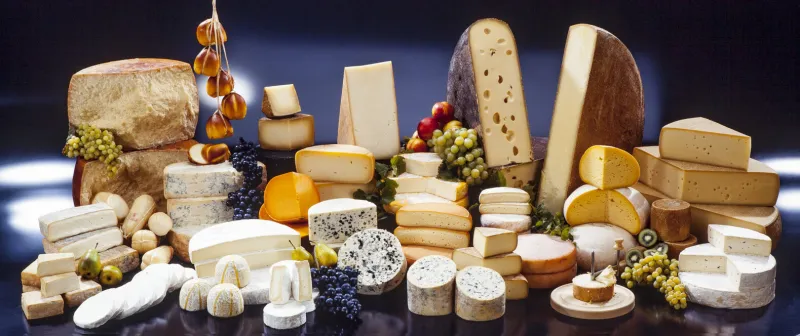 large assortment of international cheese specialities on black background