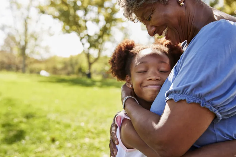 close up of granddaughter hugging grandmother in park
