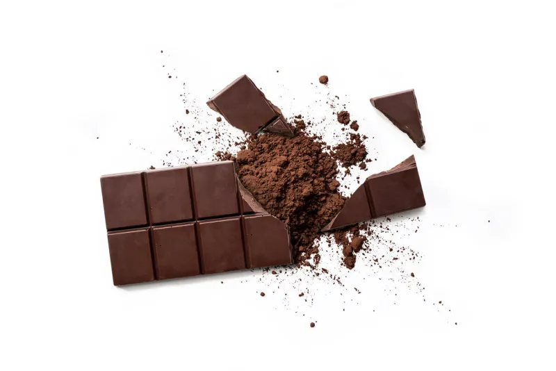top view of broken dark chocolate bar and chocolate powder isolated on white table