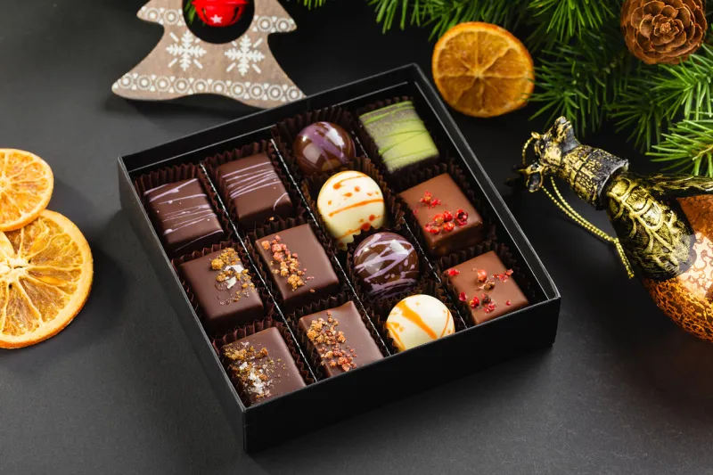 assortment of colorful handmade chocolate candies in black box with christmas decorations exclusive luxury bonbons product concept for chocolatier