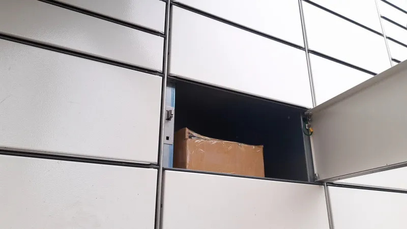 courier puts cardboard package into parcel locker