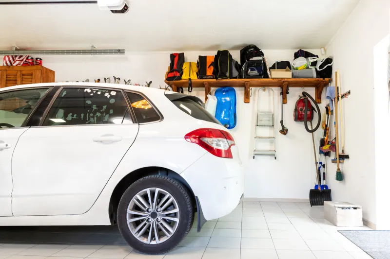 home suburban car garage interior with wooden shelf , tools and equipment stuff storage warehouse on white wall indoors vehicle parked at house parking background
