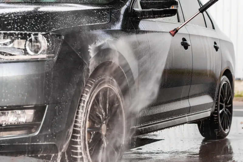 a man is washing a car at self service car wash high pressure vehicle washer machine sprays foam