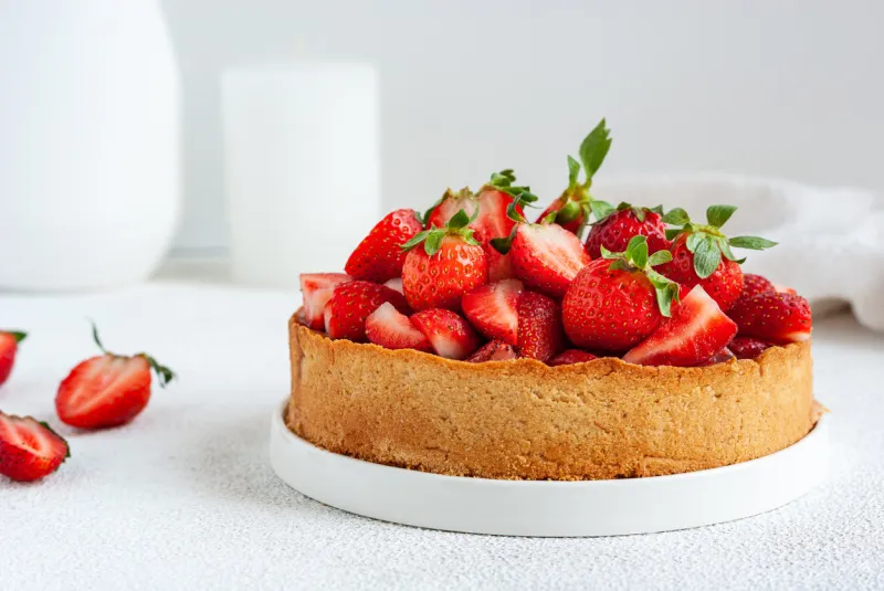 whole summer vegan strawberry pie on white table, close-up