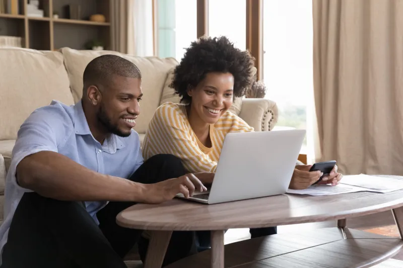 happy young black couple using laptop, looking at screen, smiling, laughing, getting good news husband and wife using online banking app on computer, paying bills, insurance mortgage fees on internet