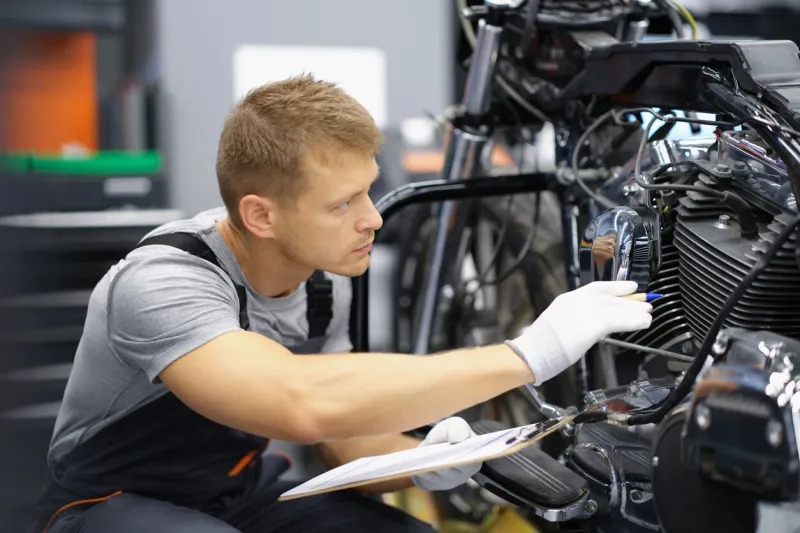 a man in the garage is checking a motorcycle, close-up wear test of parts, engine and suspension service station specialist