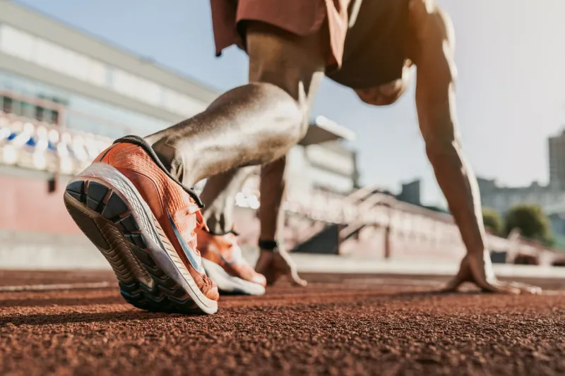 close up of male athlete getting ready to start running on track focus on sneakers