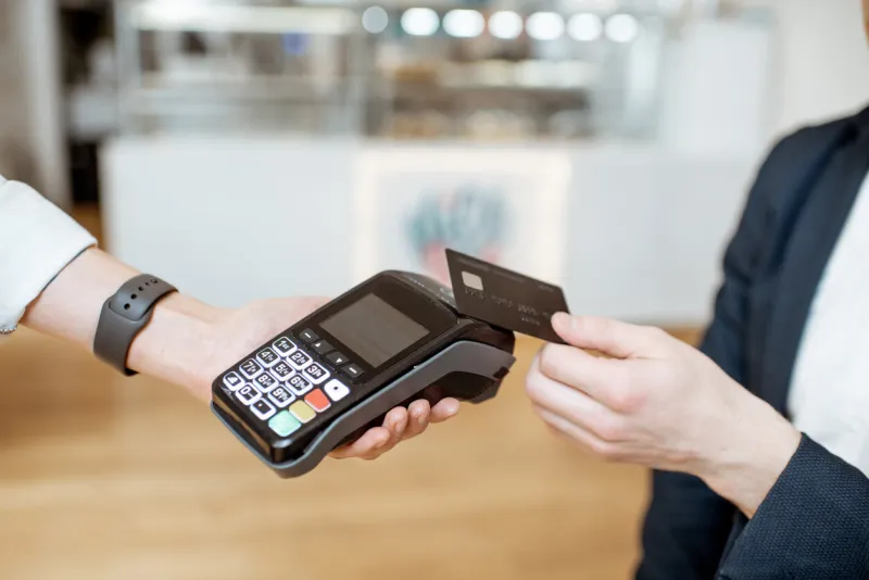 businessman paying contactless with bank card at the cafe, close-up view