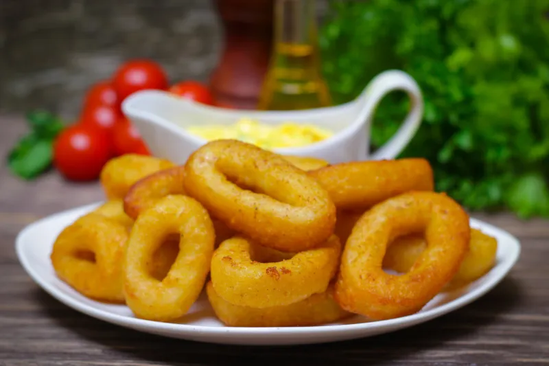 deep fried calamari with sauce and salad on a wooden background