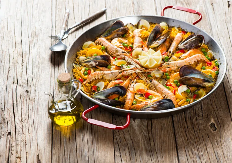 spanish dish paella with seafood in traditional pan on a rustic wooden table