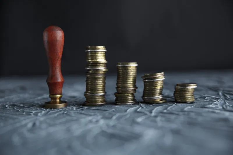 judge's hand holding gavel over stacked golden coins