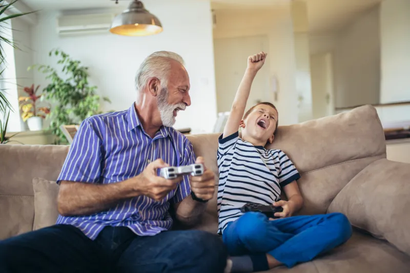 grandfather and grandson are playing video games at home