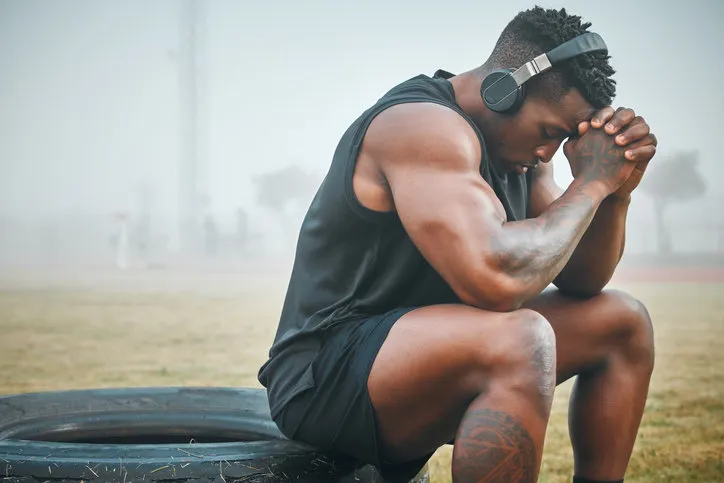 shot of a muscular young man wearing headphones while exercising outdoors