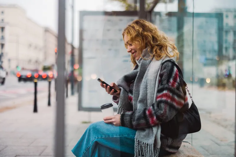 young woman using smart phone at bus station