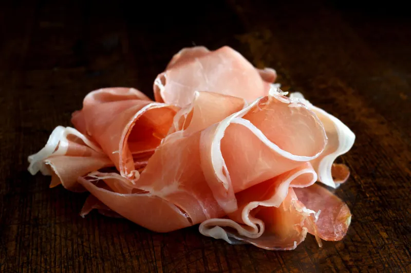 prosciutto ham isolated on dark wood