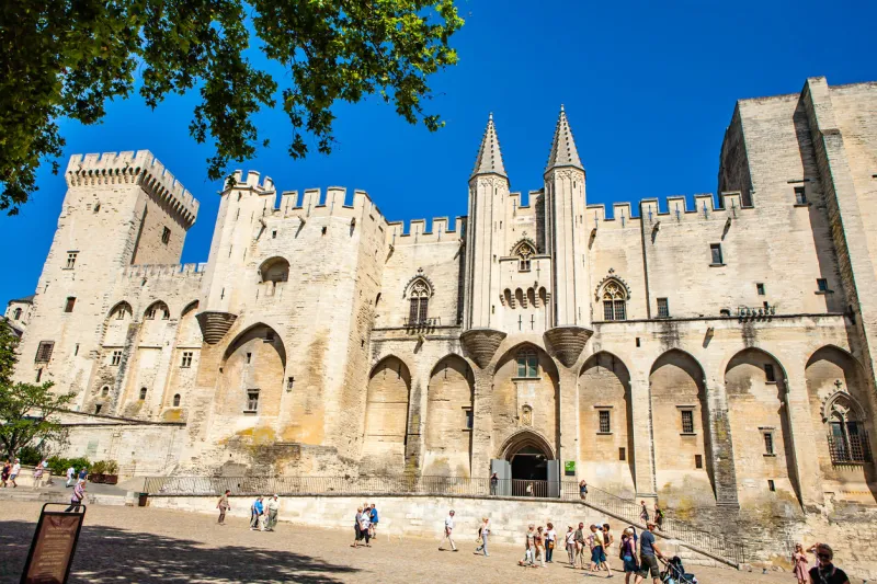 avignon, france - june 26, 2012  facade of the palace of the popes (palais des papes) in france in front of the photo is a square with almost no people