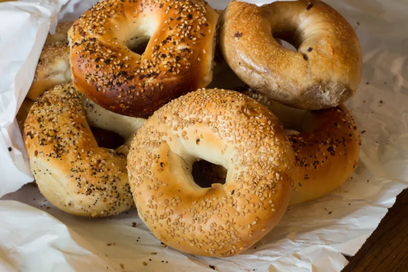 variety of authentic new york style bagels with seeds in a paper bag