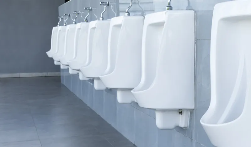 men's room with white porcelain urinals in line in gas station