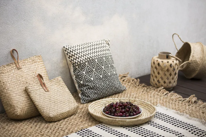 rattan bags and pillow on blanket with cherries in a bowl on bright terrace real photo