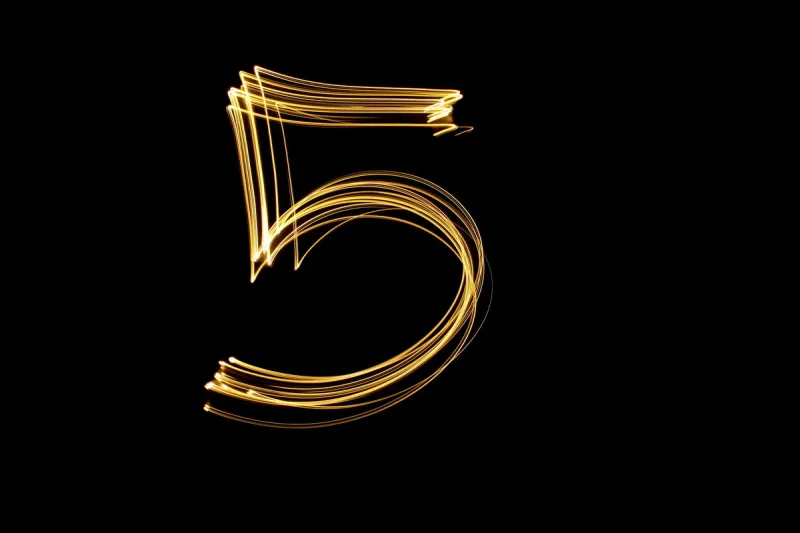 long exposure, light painting photography single number in a vibrant neon metallic yellow gold colour against a black background