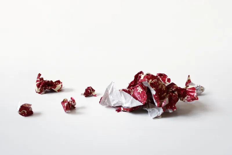 a perspective shot of crumpled balled pieces of red christmas or holiday wrap, laid out on a flat surface a perfect template to photoshop clearcut items onto for a festive layout