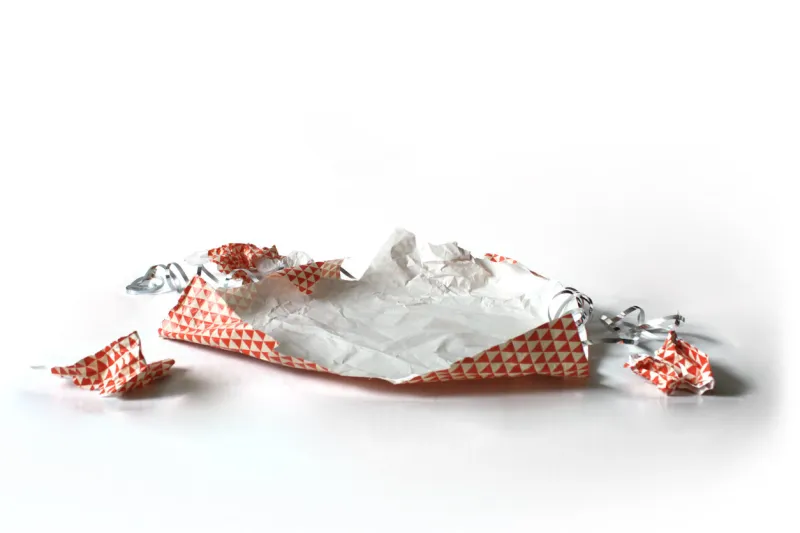 series of unwrapped crumpled non-denominational red gift wrap shot at various angles isolated on white perfect template for retouching gift products onto