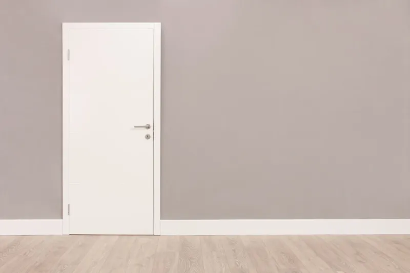 shot of a closed white door on a gray wall in an empty room