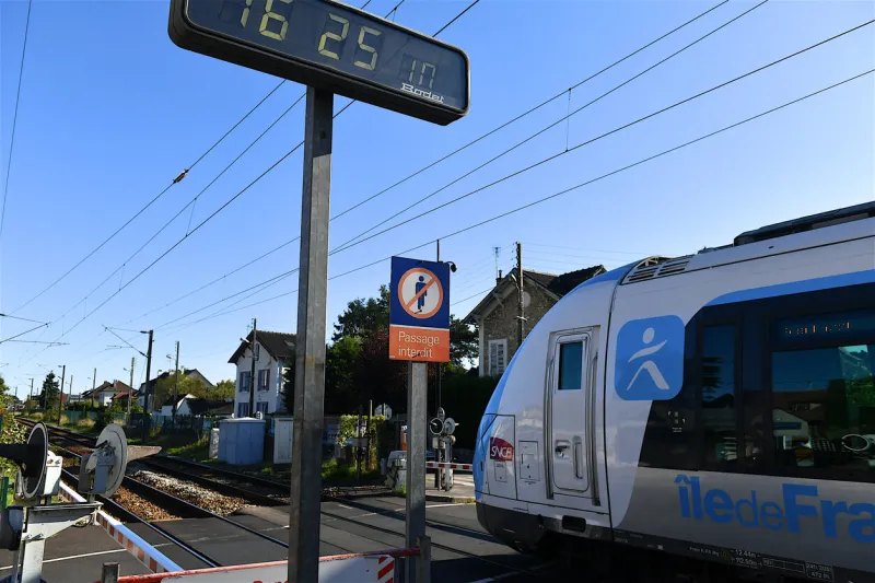 paris region, france-10 08 2021 commuter train leaving a station and passing at the level crossing